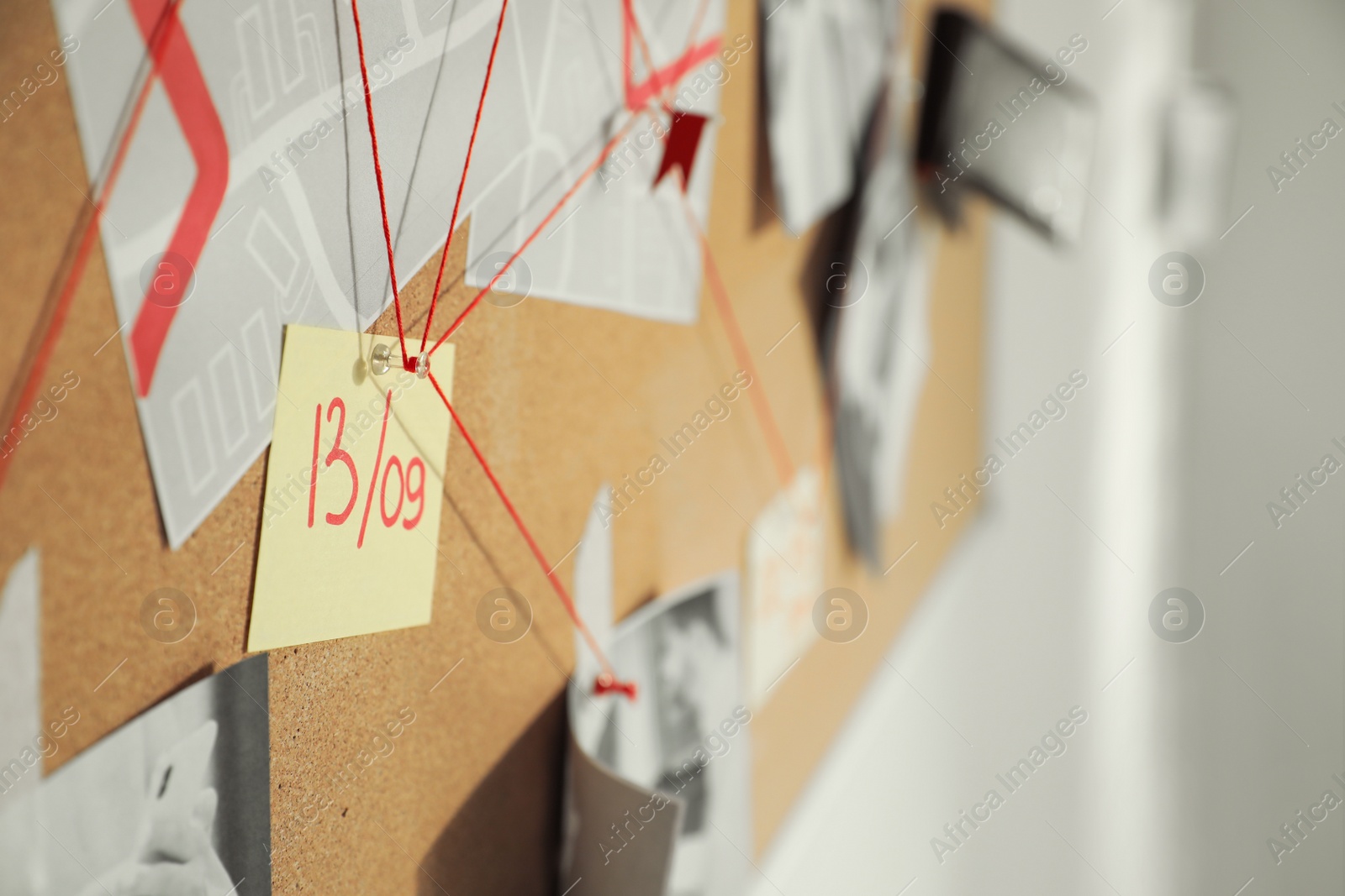 Photo of Detective board with crime scene photos and red threads, closeup