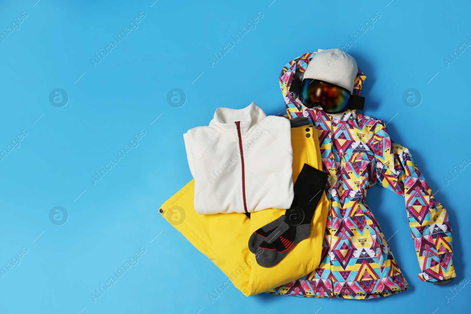 Photo of Stylish winter sport clothes on light blue background, flat lay. Space for text