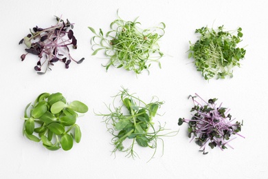 Different microgreens on white background, top view