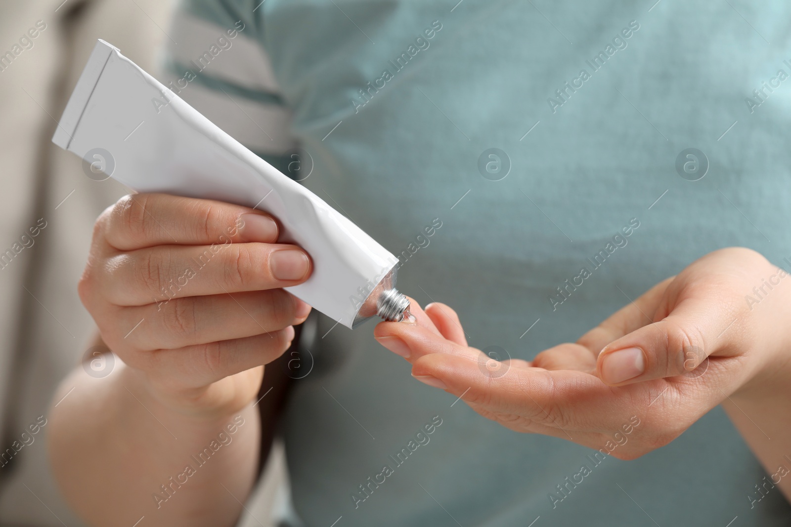 Photo of Woman applying ointment from tube onto her finger, closeup