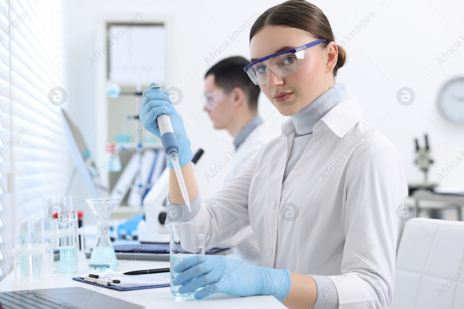 Photo of Scientist dripping sample into beaker in laboratory