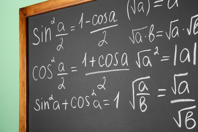 Photo of Chalkboard with many different math formulas on green wall, closeup