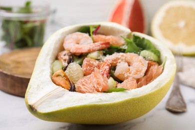 Photo of Delicious pomelo salad with shrimps in half of fruit on table, closeup