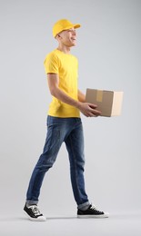 Happy courier with parcel on light grey background