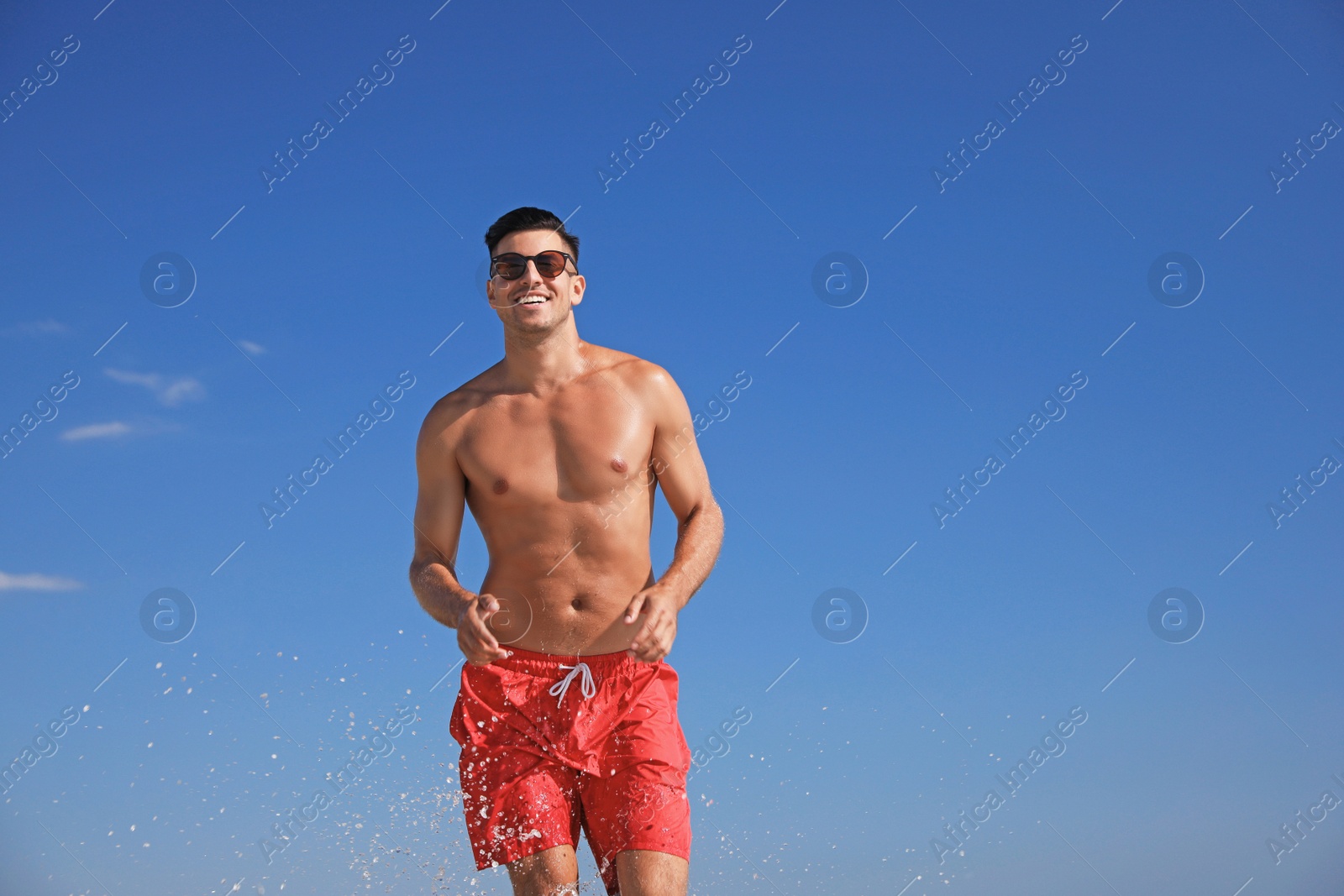 Photo of Handsome man with attractive body against blue sky