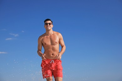 Photo of Handsome man with attractive body against blue sky