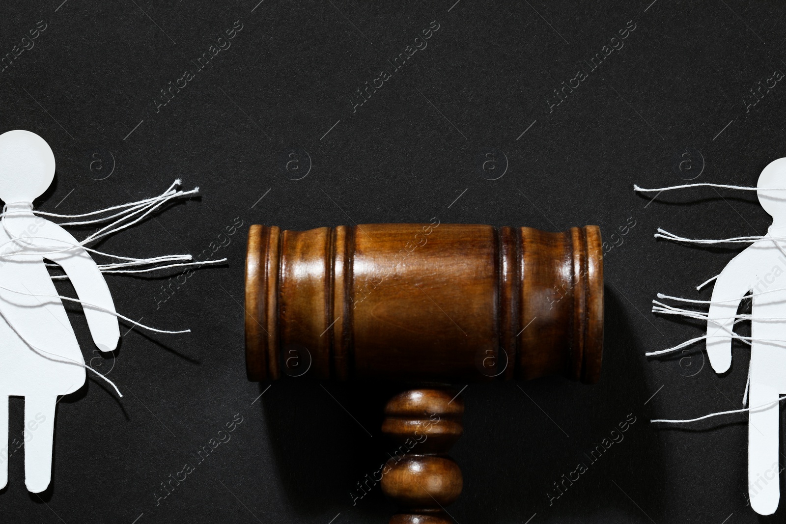 Photo of Divorce concept. Paper human figures with cut white threads and gavel on black background, flat lay