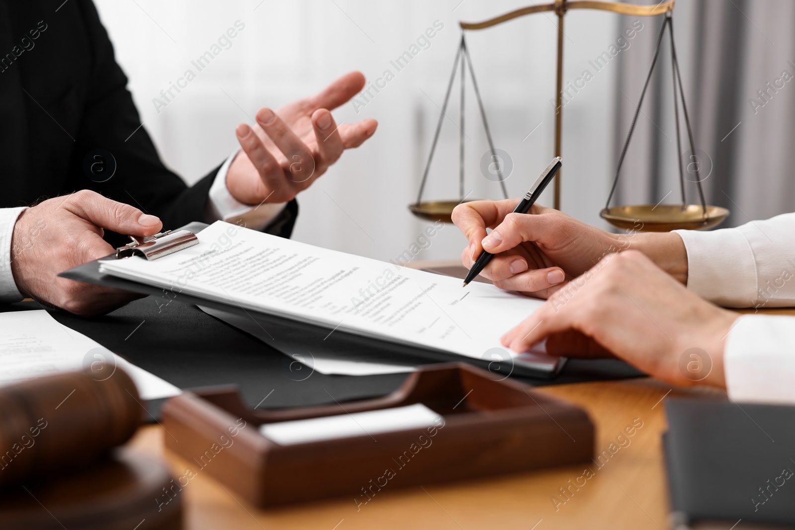 Photo of Woman signing document in lawyer's office, closeup