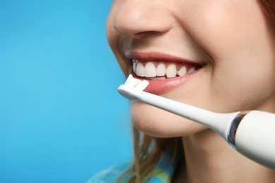 Photo of Young woman with electric toothbrush on color background, closeup. Space for text