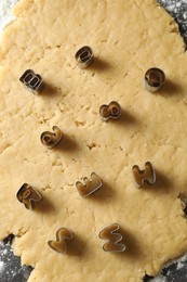 Photo of Making shortcrust pastry. Raw dough and cookie cutters on table, top view