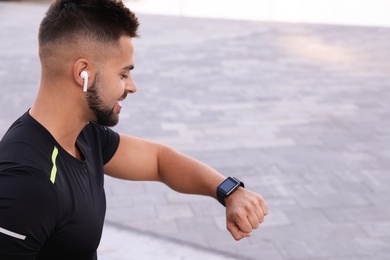 Photo of Young man with wireless headphones and smart watch listening to music on stairs