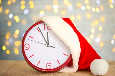 Clock with Santa hat showing five minutes until midnight on blurred background. New Year countdown