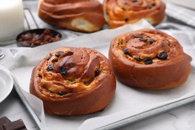 Photo of Delicious rolls with raisins on white table, closeup. Sweet buns