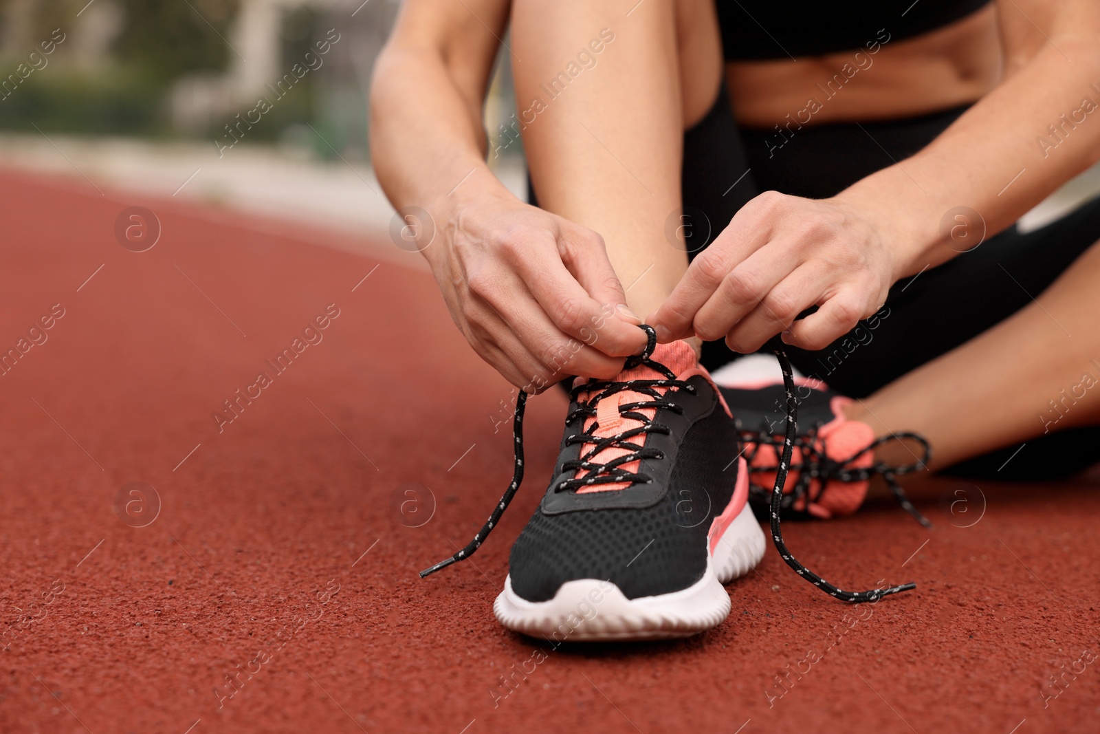 Photo of Woman tying shoelaces before training outdoors. closeup. Space for text