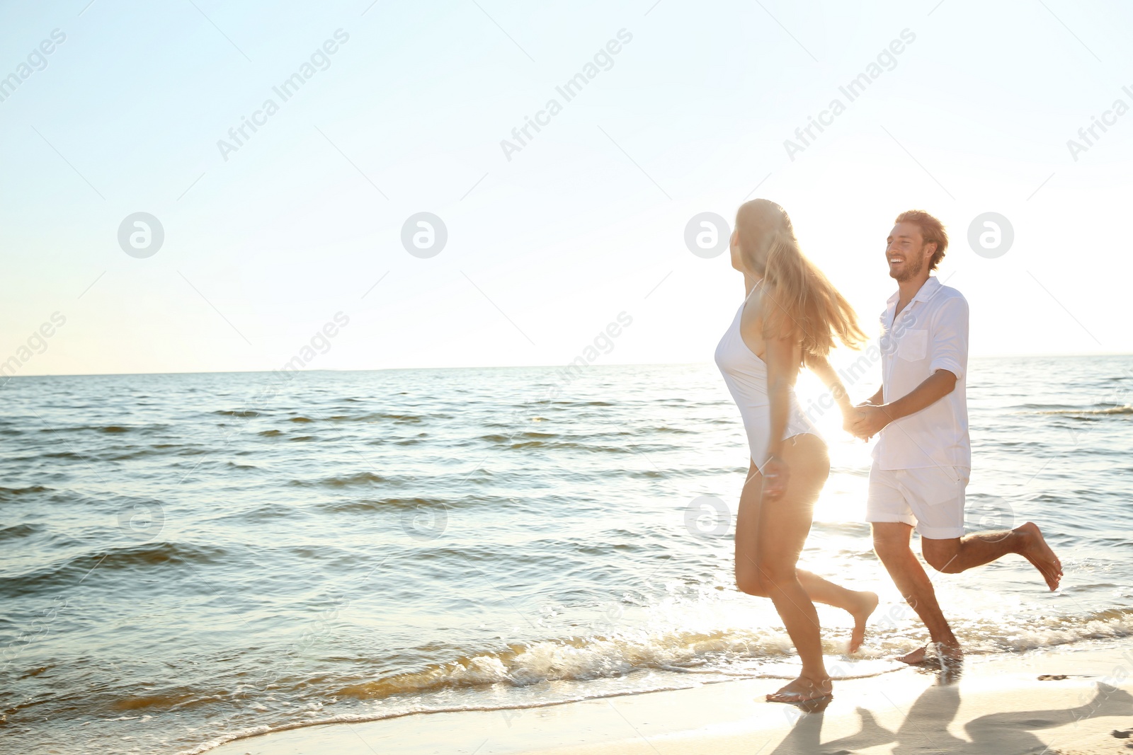 Photo of Happy young couple in beachwear running together on seashore