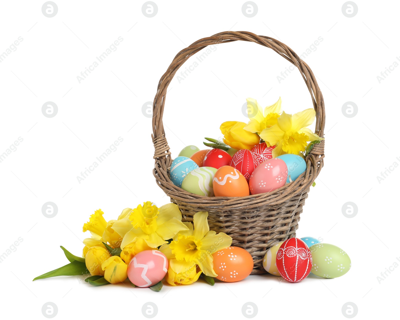 Photo of Wicker basket with painted Easter eggs and flowers on white background