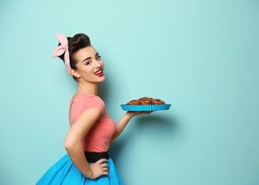 Funny young housewife with homemade pastry on color background