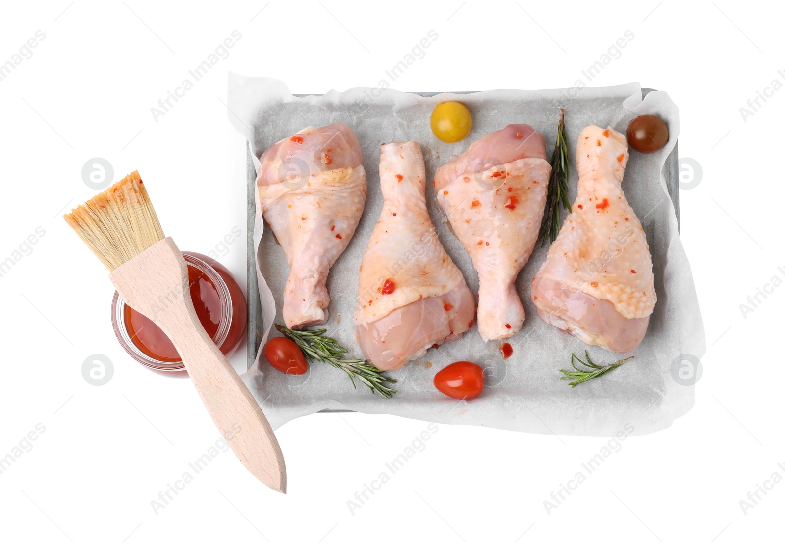 Photo of Marinade, brush, raw chicken drumsticks, rosemary and tomatoes isolated on white, top view