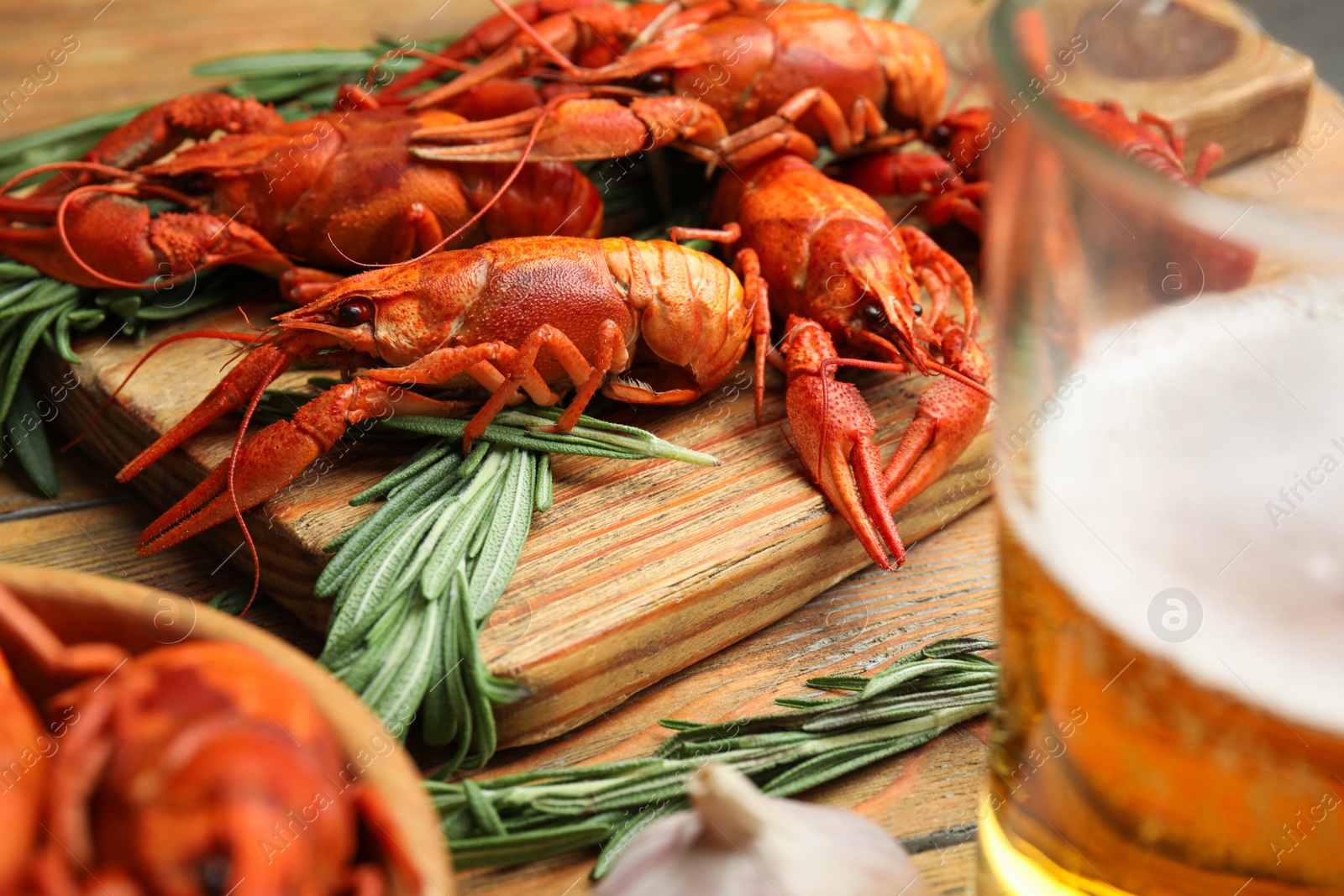 Photo of Delicious red boiled crayfishes on wooden board, closeup