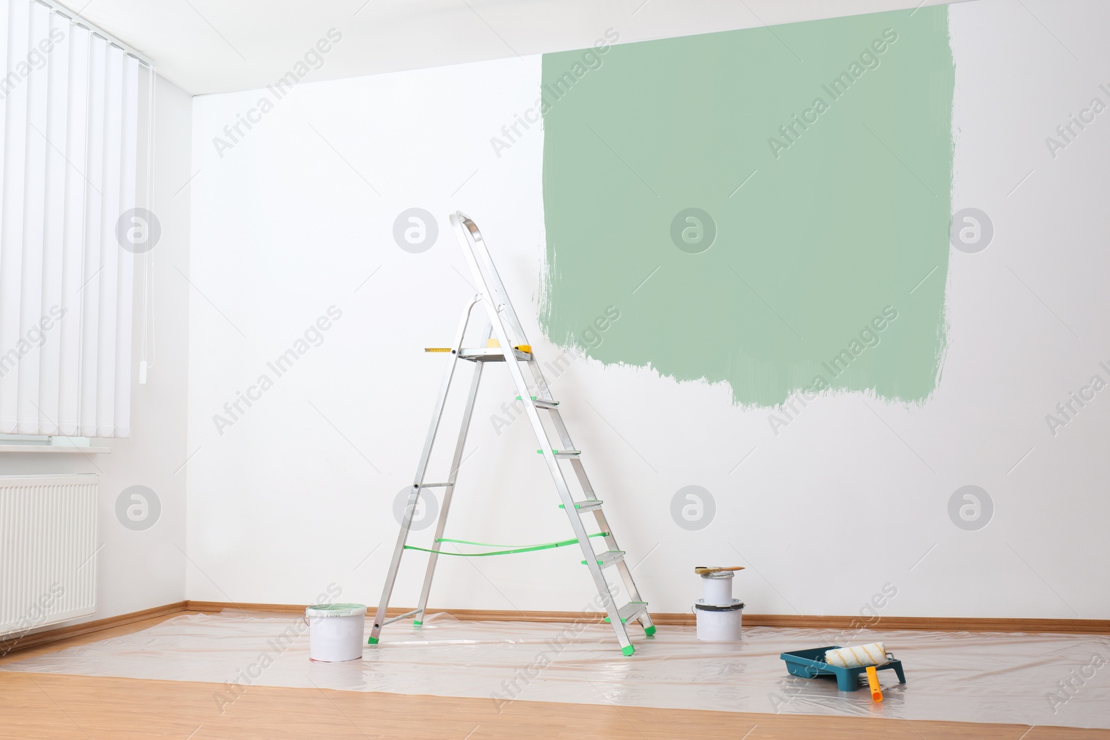 Image of Stepladder and painting tools near wall in empty room