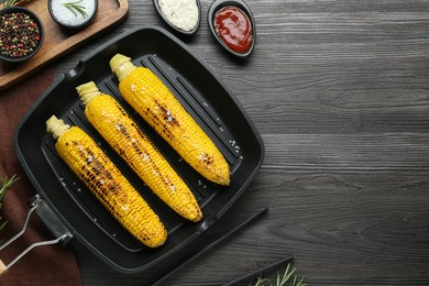 Photo of Flat lay composition with tasty grilled corn on dark grey wooden table. Space for text