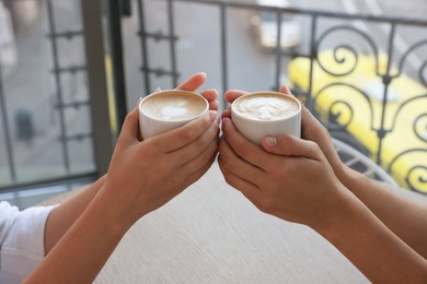 Friends drinking coffee at wooden table in cafe, closeup