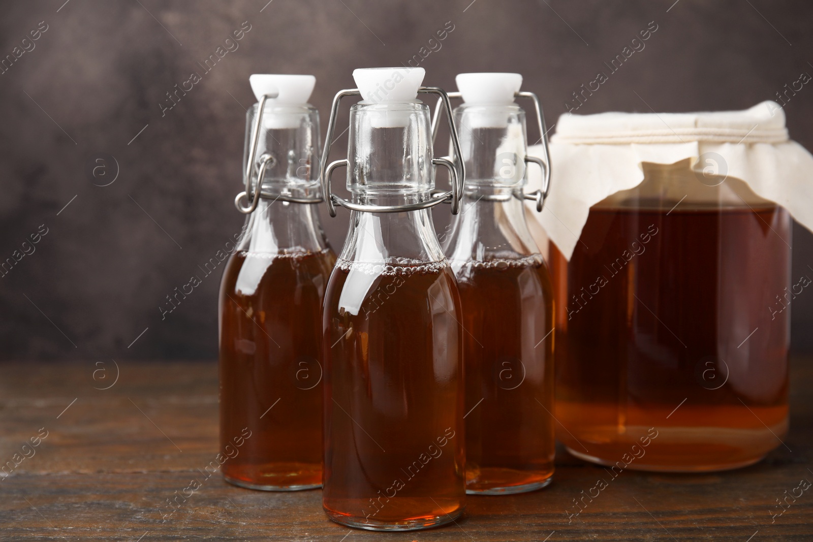 Photo of Tasty kombucha in jar and bottles on wooden table