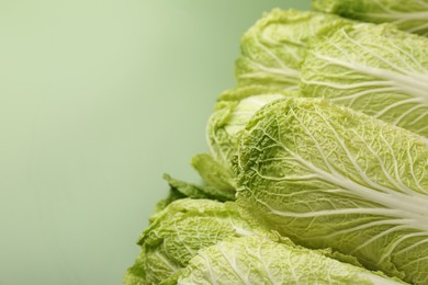 Fresh ripe Chinese cabbages on pale green background, closeup. Space for text