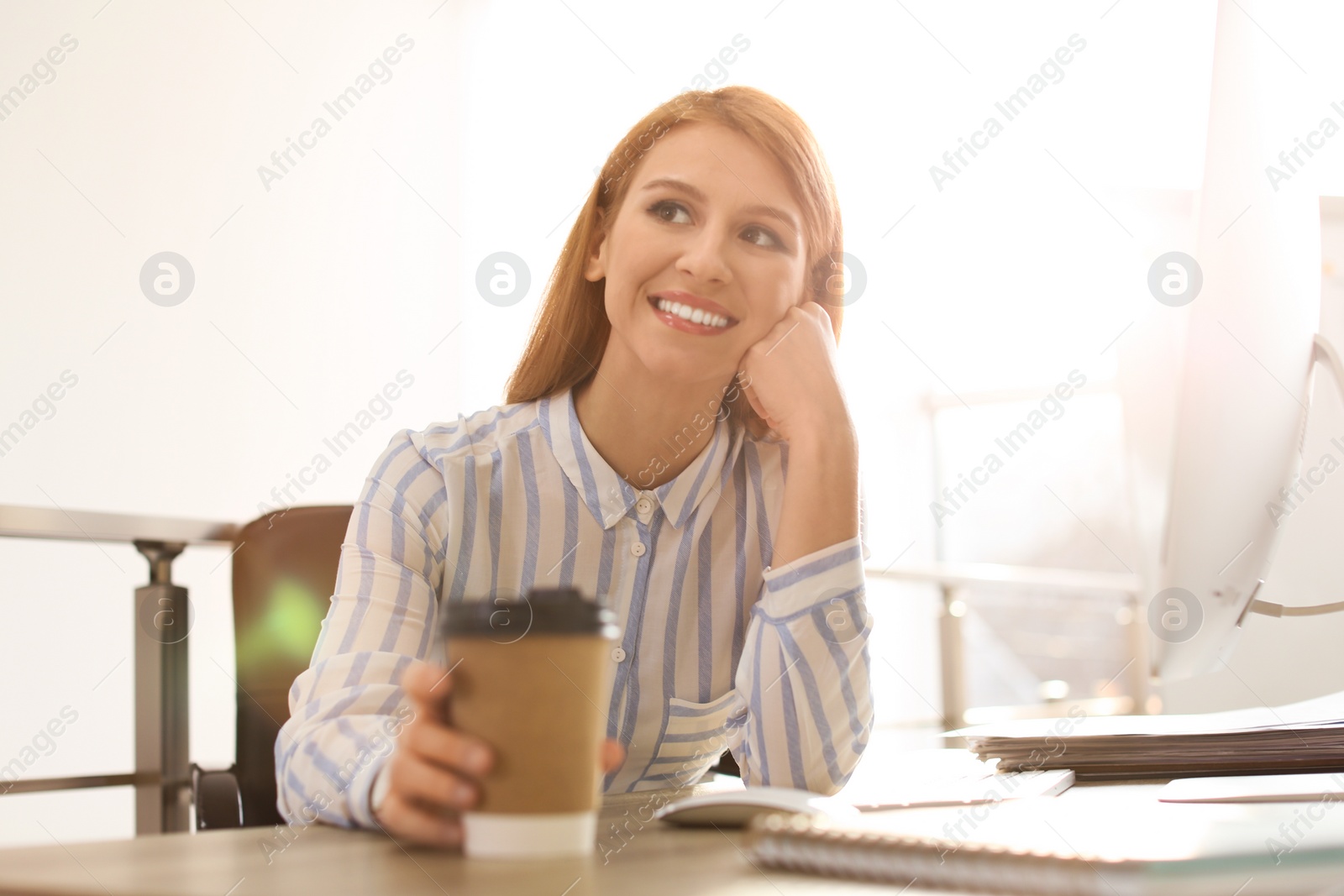 Photo of Young businesswoman with cup of coffee relaxing at table in office during break