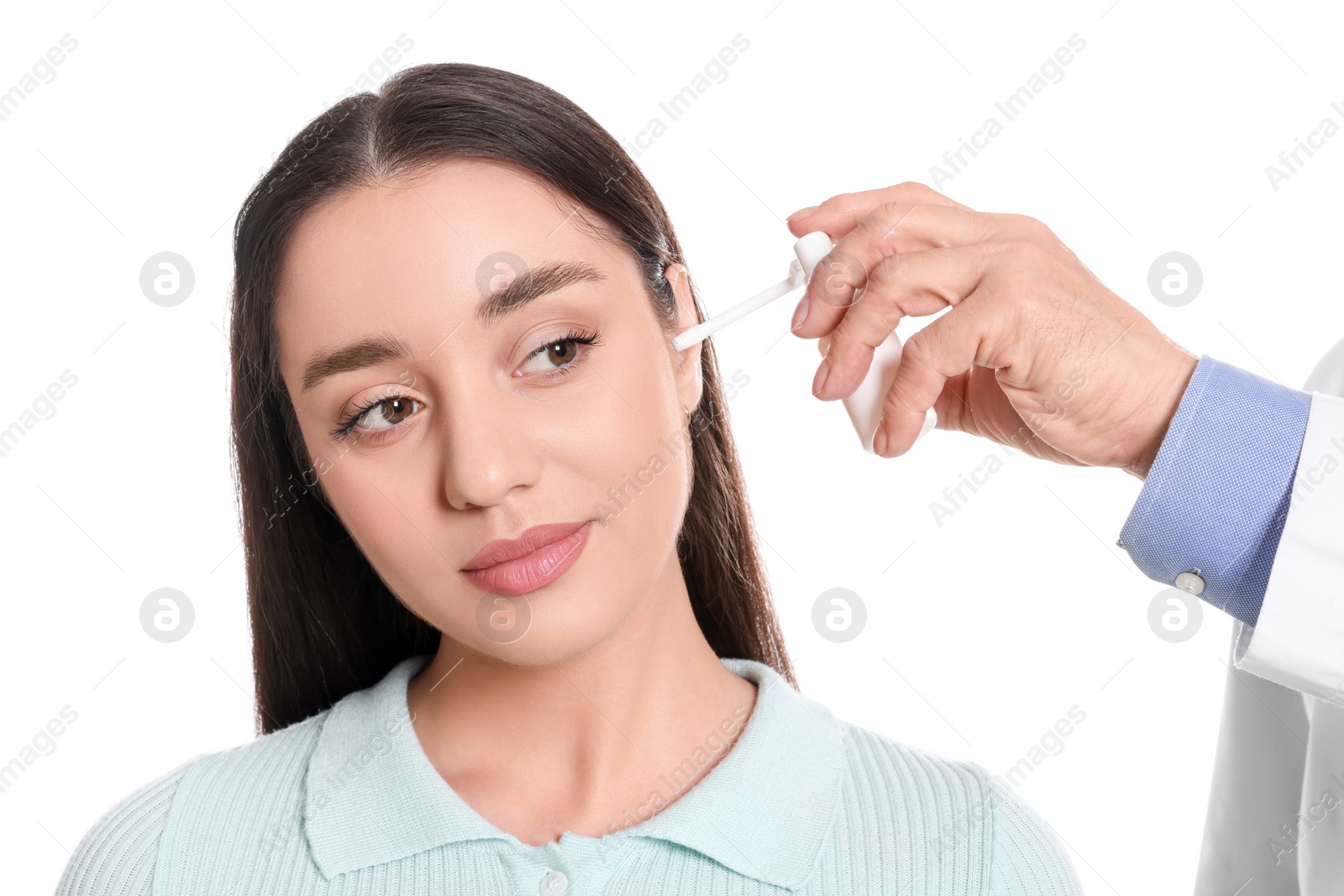 Photo of Doctor spraying medication into woman's ear on white background