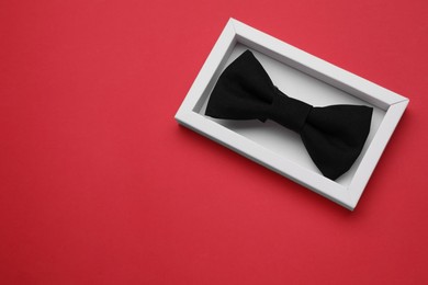 Photo of Stylish black bow tie on red background, top view. Space for text