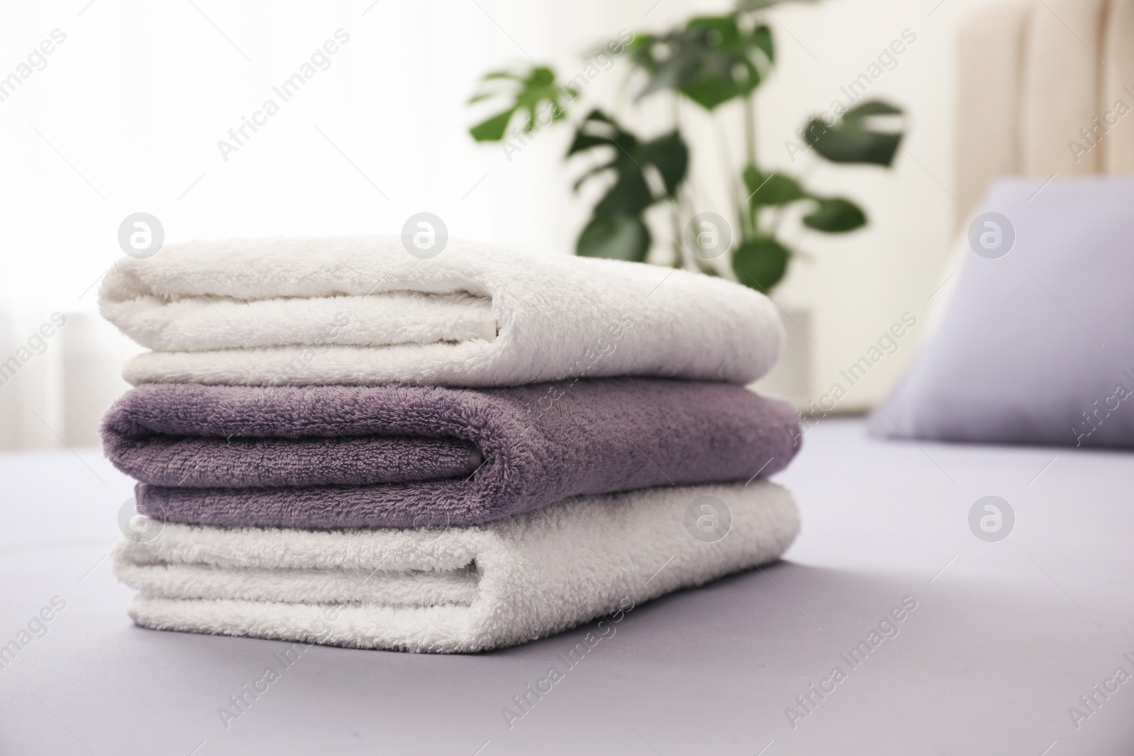 Photo of Stack of clean towels on bed indoors