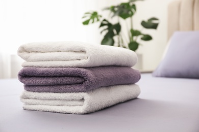 Photo of Stack of clean towels on bed indoors