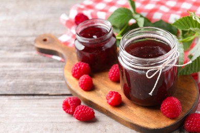 Photo of Delicious raspberry jam and fresh berries on wooden table. Space for text