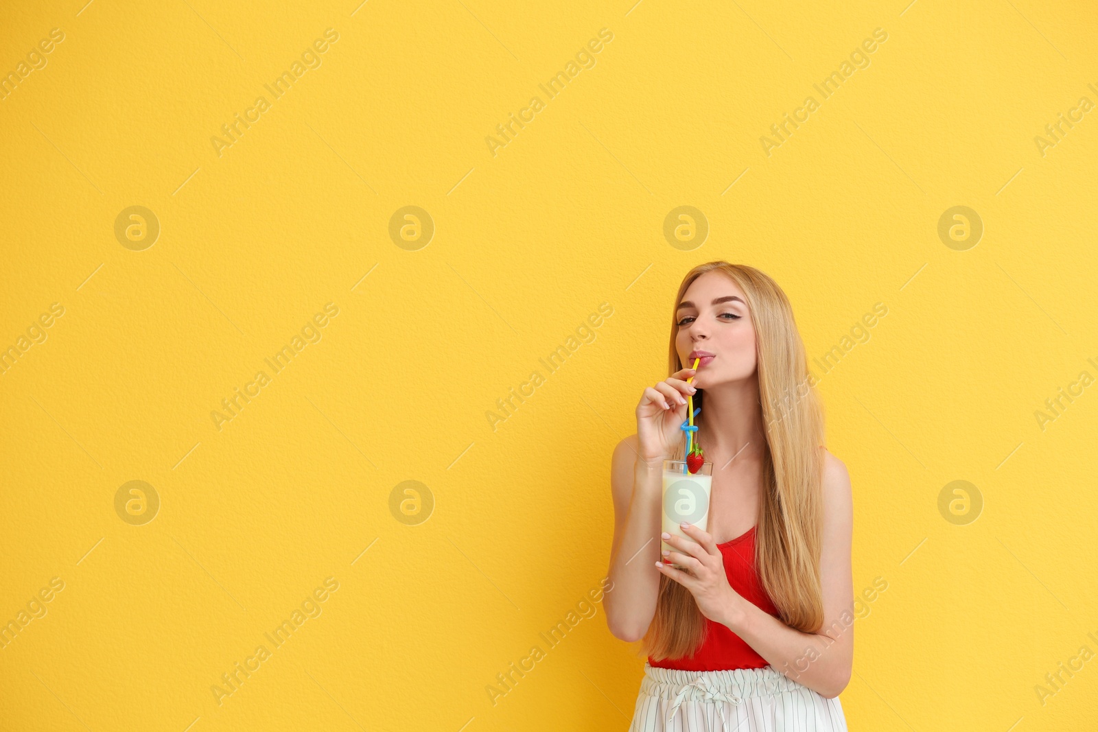 Photo of Young woman with glass of delicious milk shake on color background