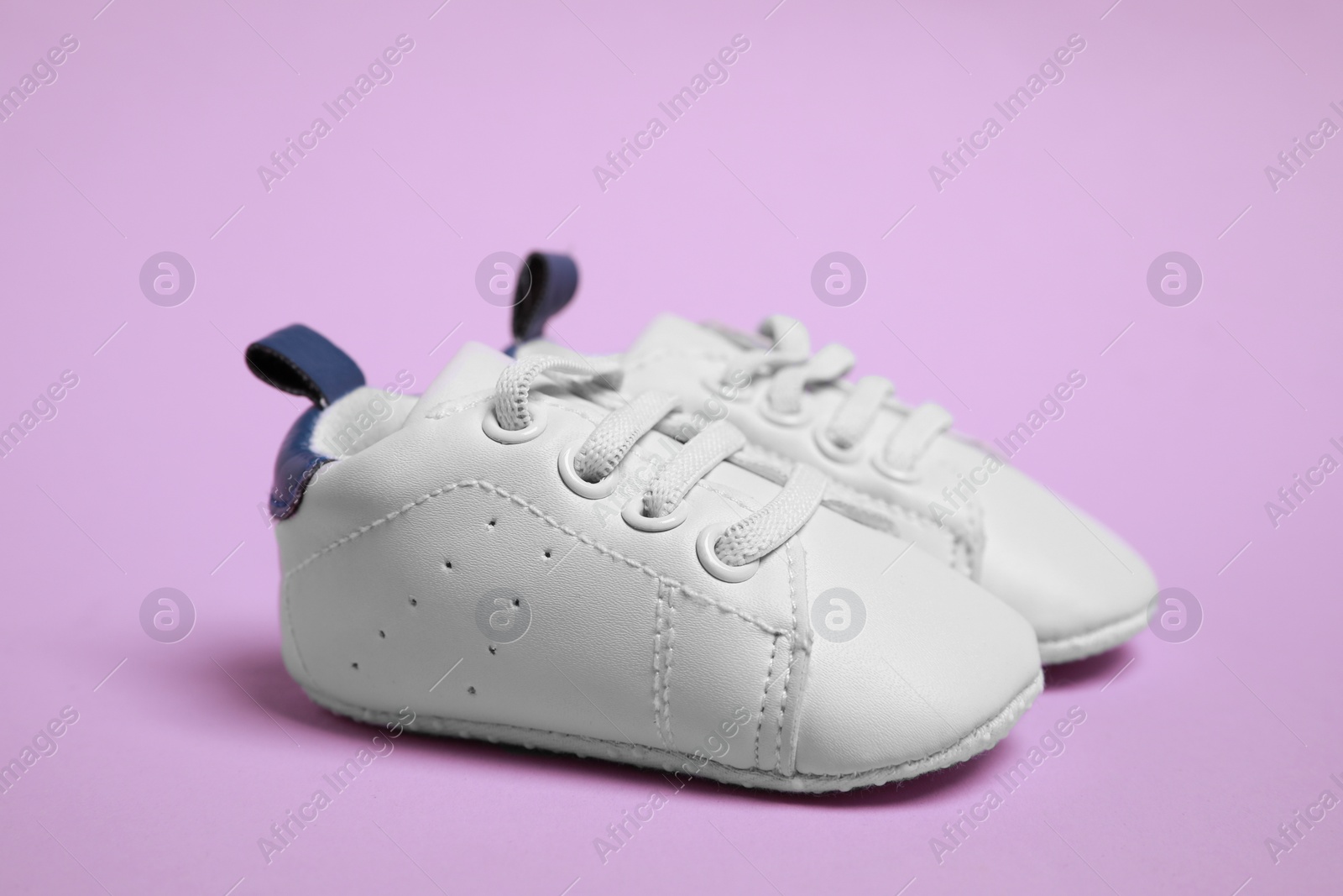 Photo of Pair of cute baby shoes on violet background