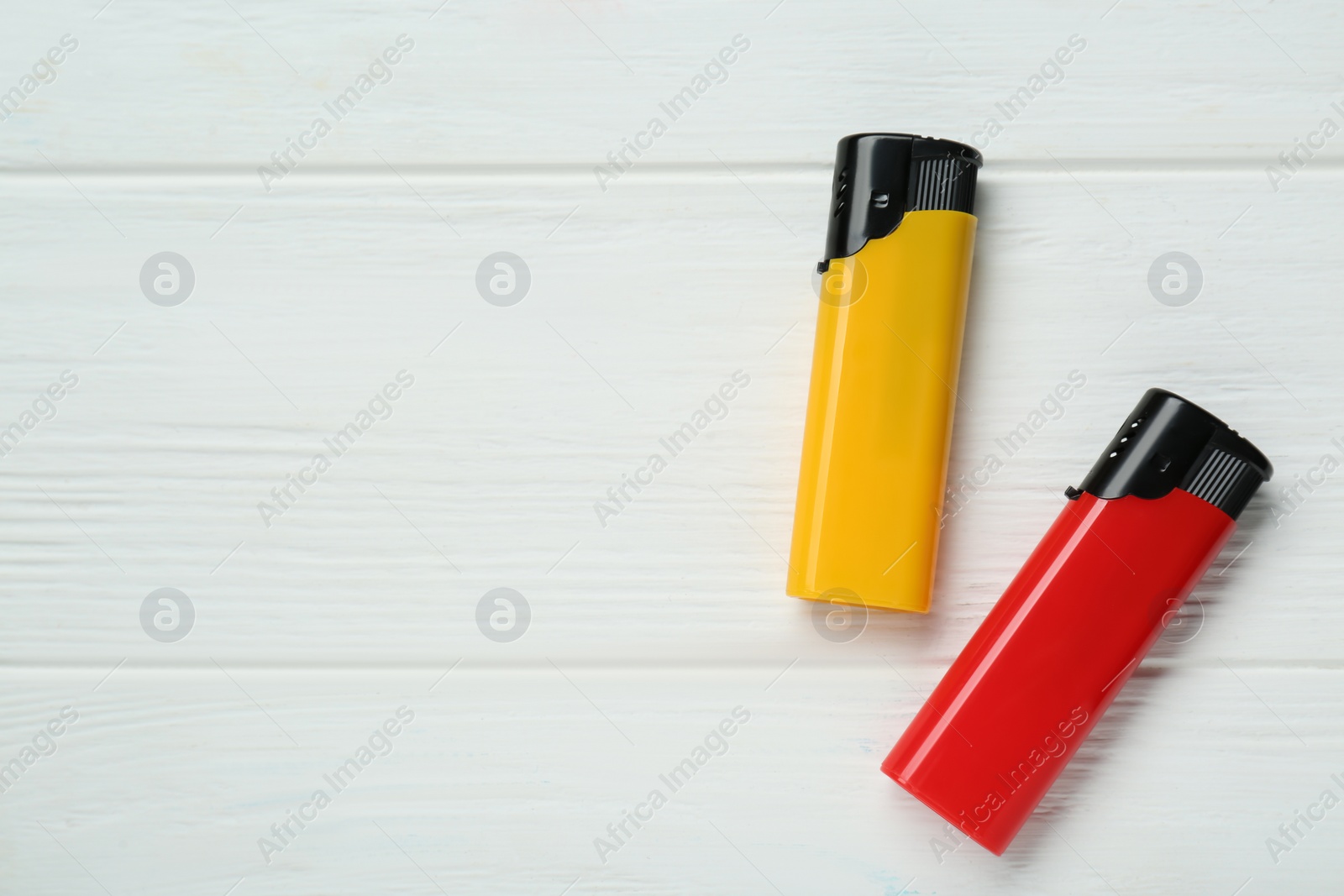 Photo of Stylish small pocket lighters on white wooden background, flat lay. Space for text