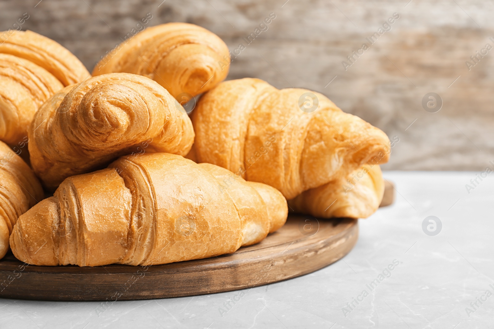 Photo of Wooden board with tasty croissants on table