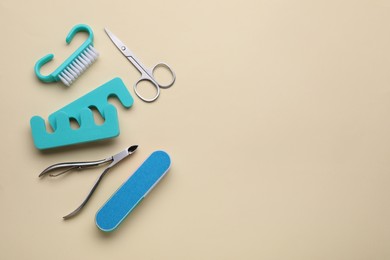 Photo of Set of pedicure tools on beige background, flat lay. Space for text
