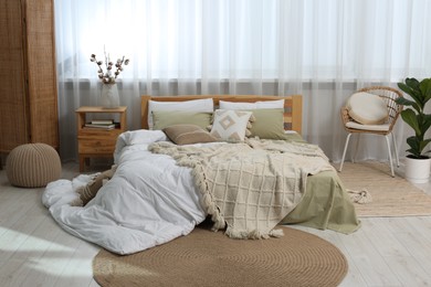Photo of Large comfortable bed with soft pillows, duvet and blanket in room. Home textile