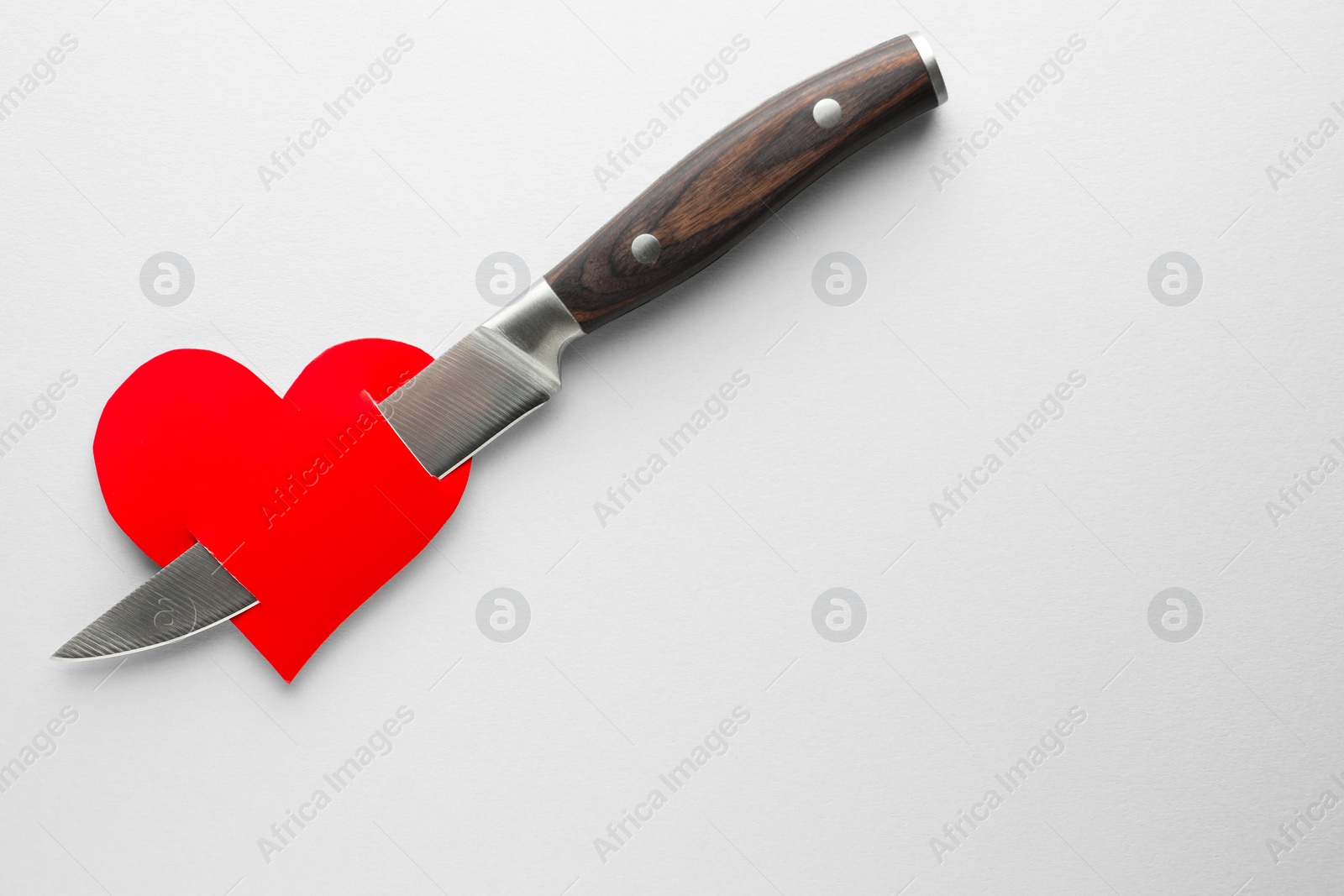 Photo of Broken heart. Red paper heart pierced with knife on white background, top view. Space for text