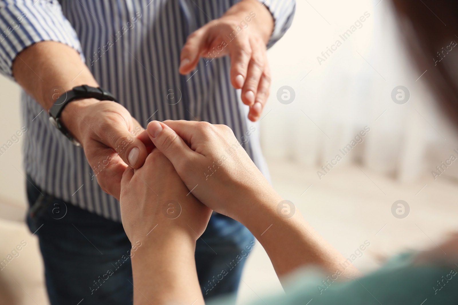 Photo of Man and woman holding hands on light background, closeup. Help and support concept