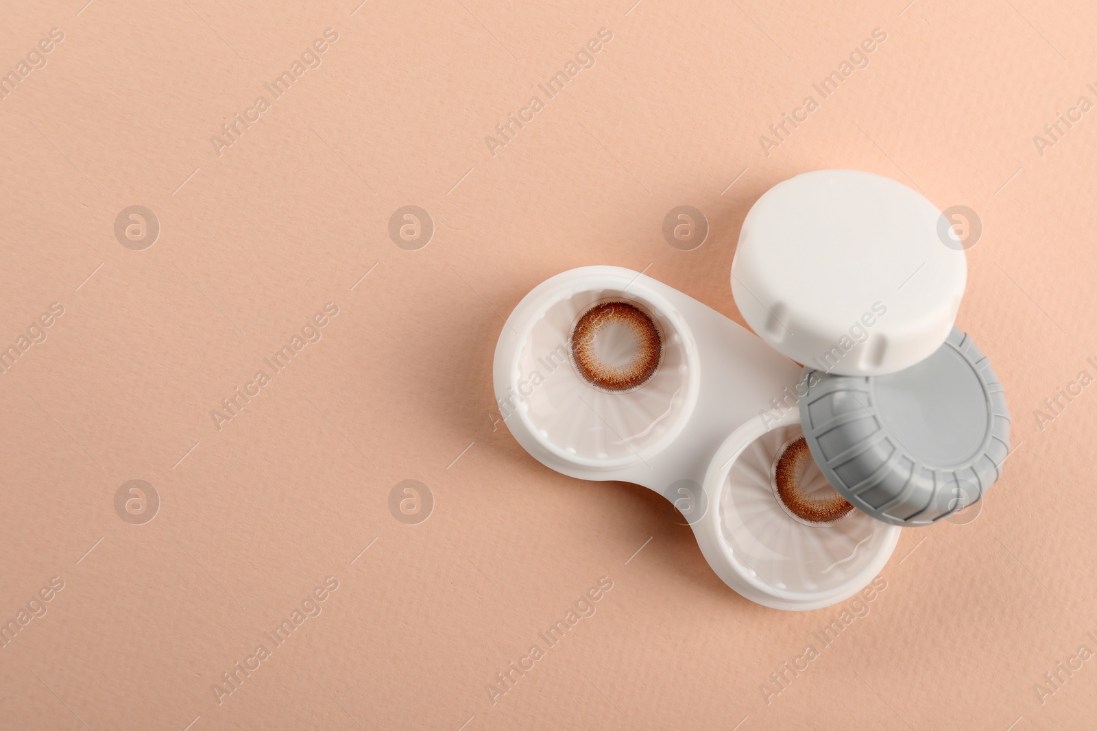 Photo of Case with color contact lenses on beige background, top view and space for text