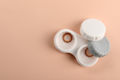 Photo of Case with color contact lenses on beige background, top view and space for text