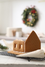 Photo of Unfinished gingerbread house and icing on white wooden table. Space for text