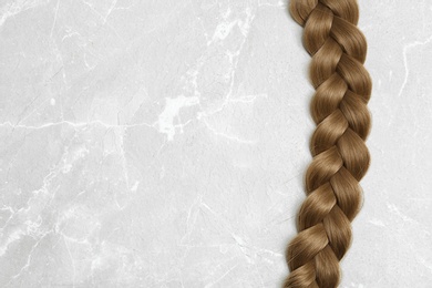Braided hair on grey background, top view with space for text