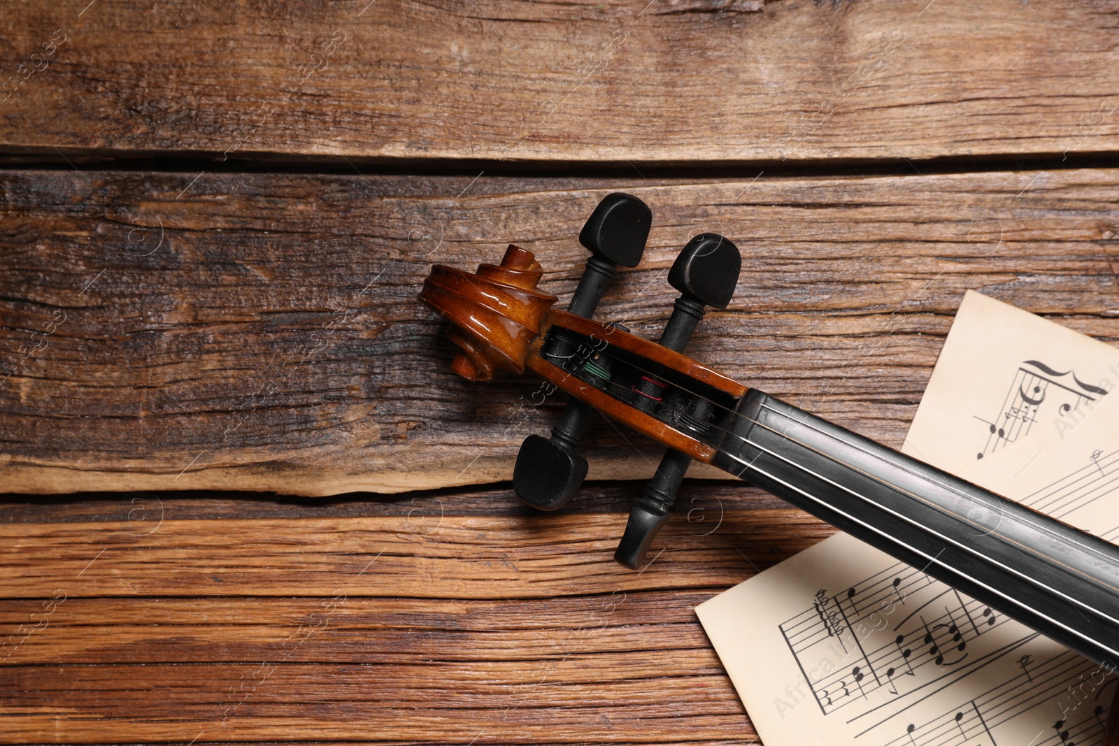 Photo of Violin and music sheets on wooden table, top view. Space for text