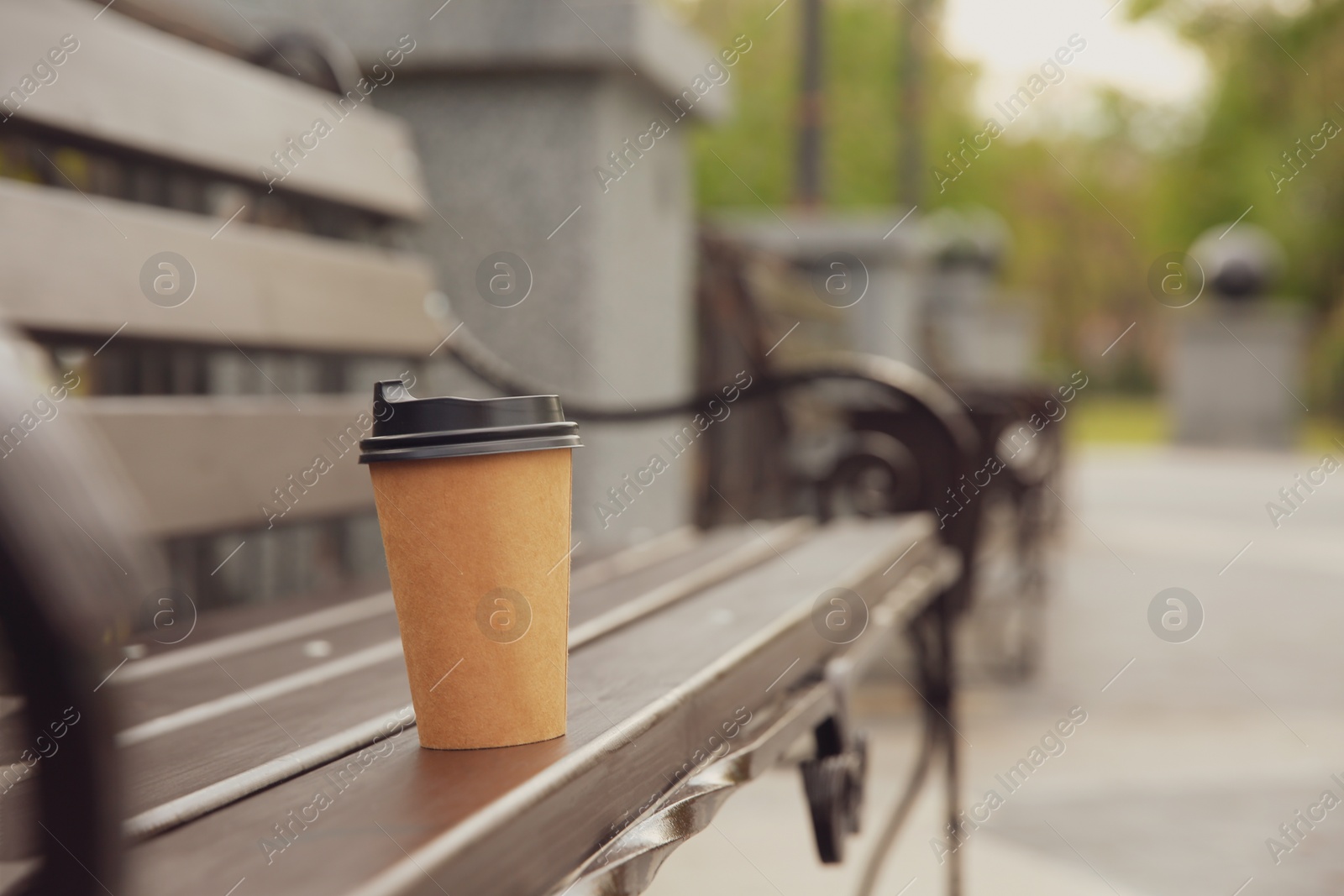 Photo of Takeaway paper coffee cup on bench outdoors, space for text