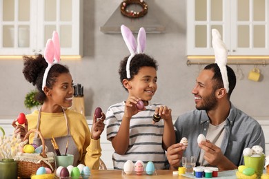 Happy African American family with Easter eggs at table in kitchen