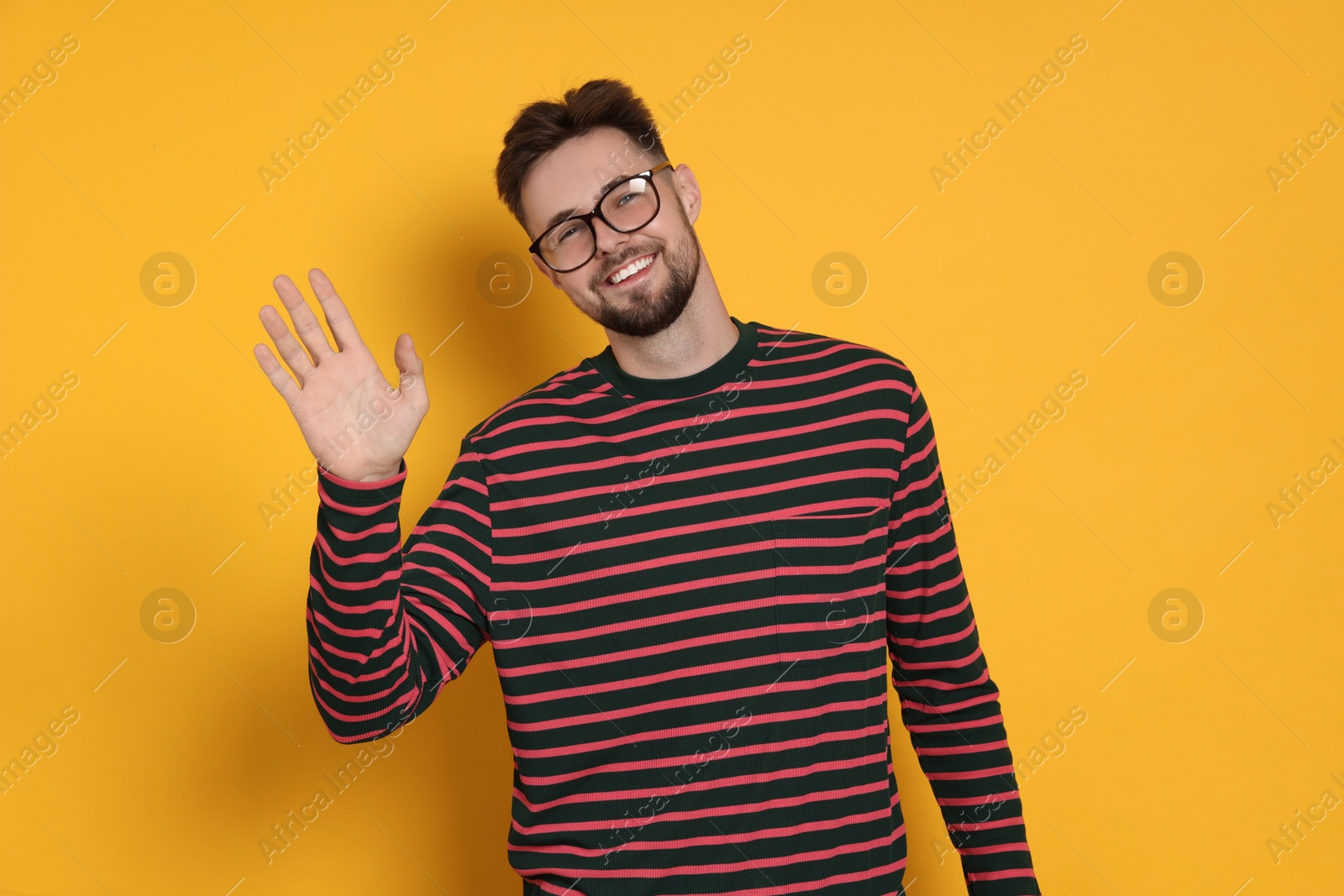 Photo of Handsome man in striped sweatshirt and eyeglasses on yellow background